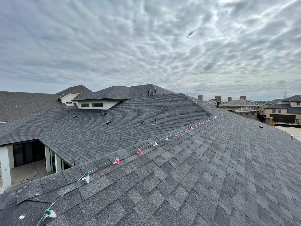 Custom-fitted Christmas bulbs aligned along a shingled roof ridge.