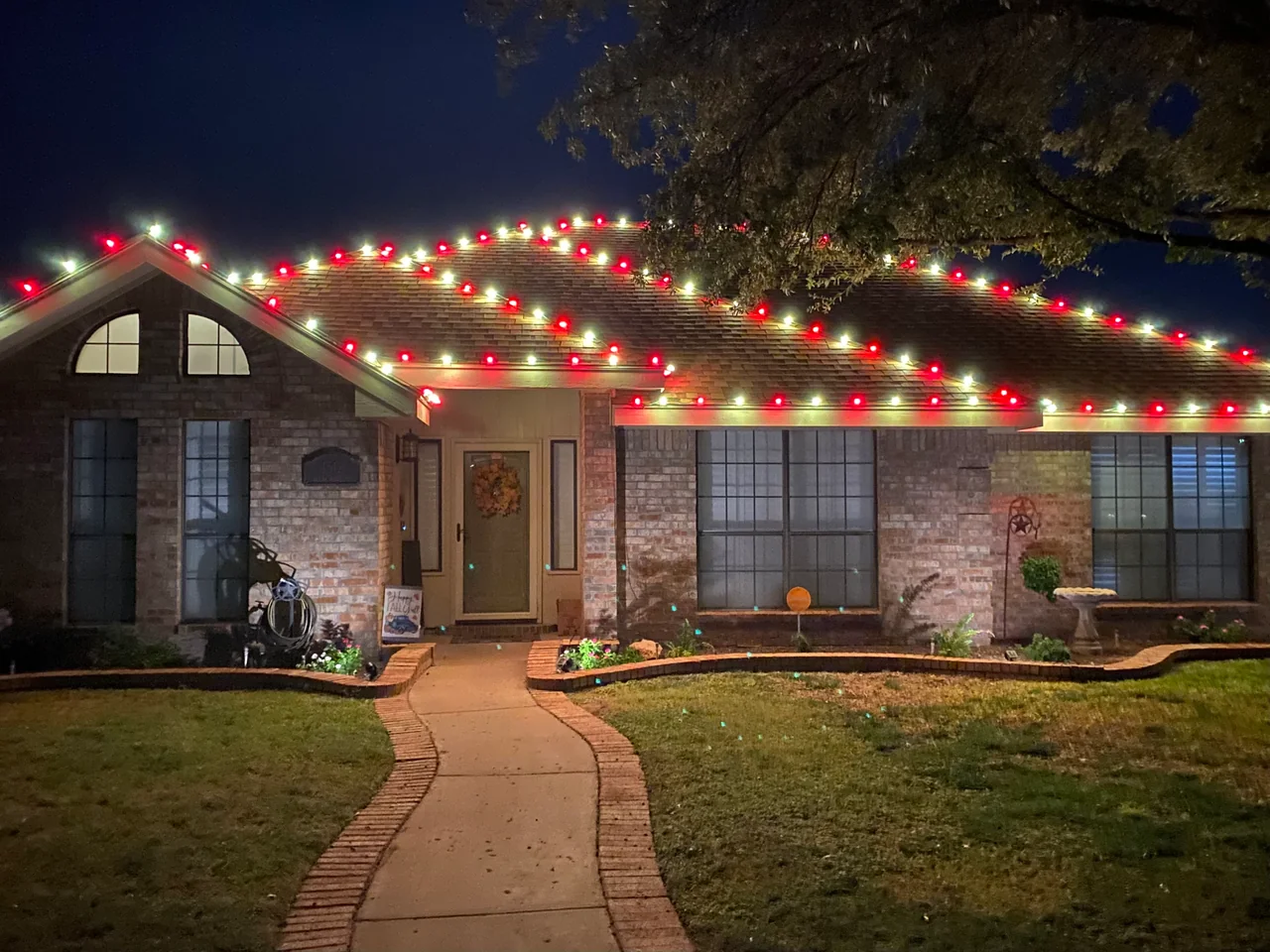 Red-and-white Christmas lights follow the ridges and eaves of a brick home.